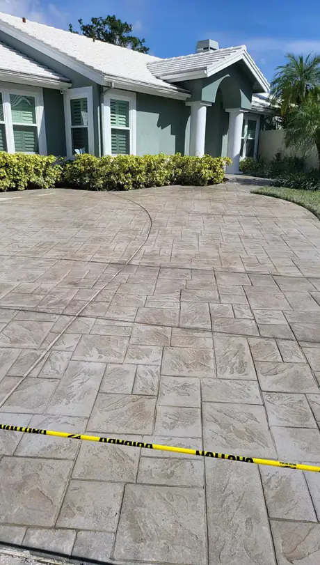 A stamped concrete driveway installation in a large tile pattern running from the street to an attached garage.