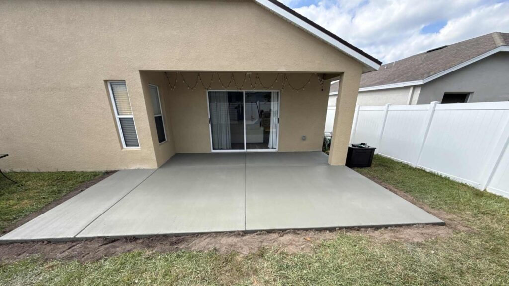 Newly poured and finished residential broom-finish concrete patio extension slab featuring clean tooled control joints in a backyard setting, installed by Crego Concrete